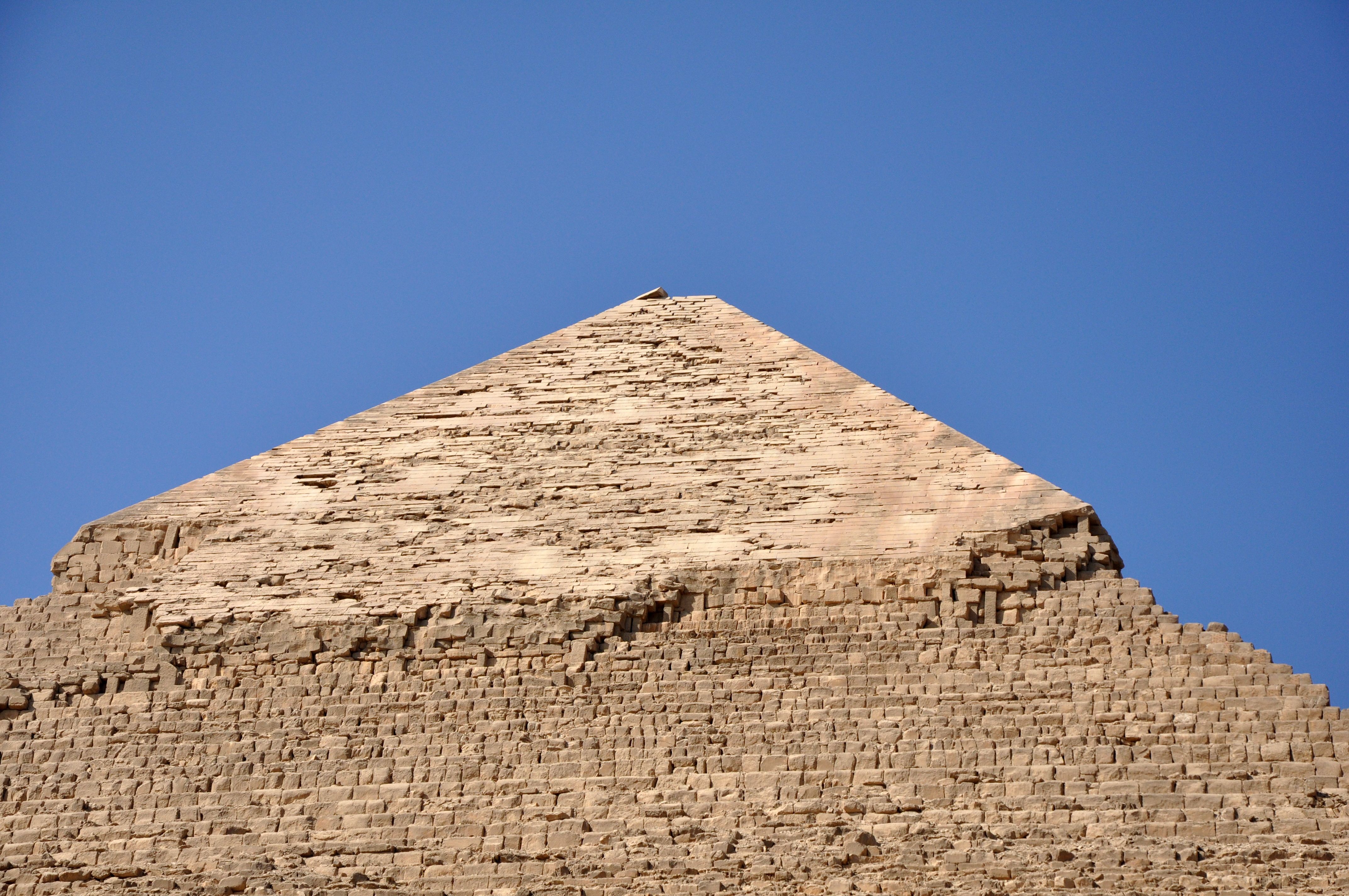 Close-up of an ancient Egyptian pyramid against a clear blue sky, showcasing its monumental architecture.