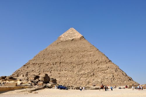 Free View of the Great Pyramid of Giza with tourists, clear blue sky highlighting this ancient wonder. Stock Photo