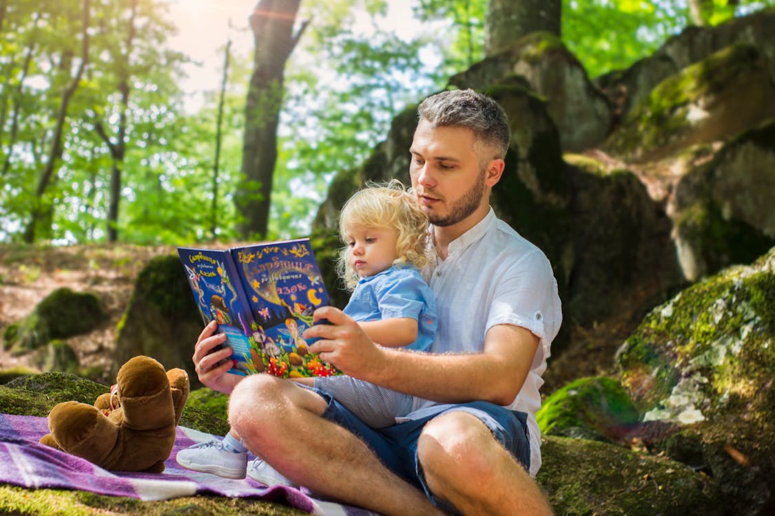 Photo Of Man And Child Reading Book During Daytime