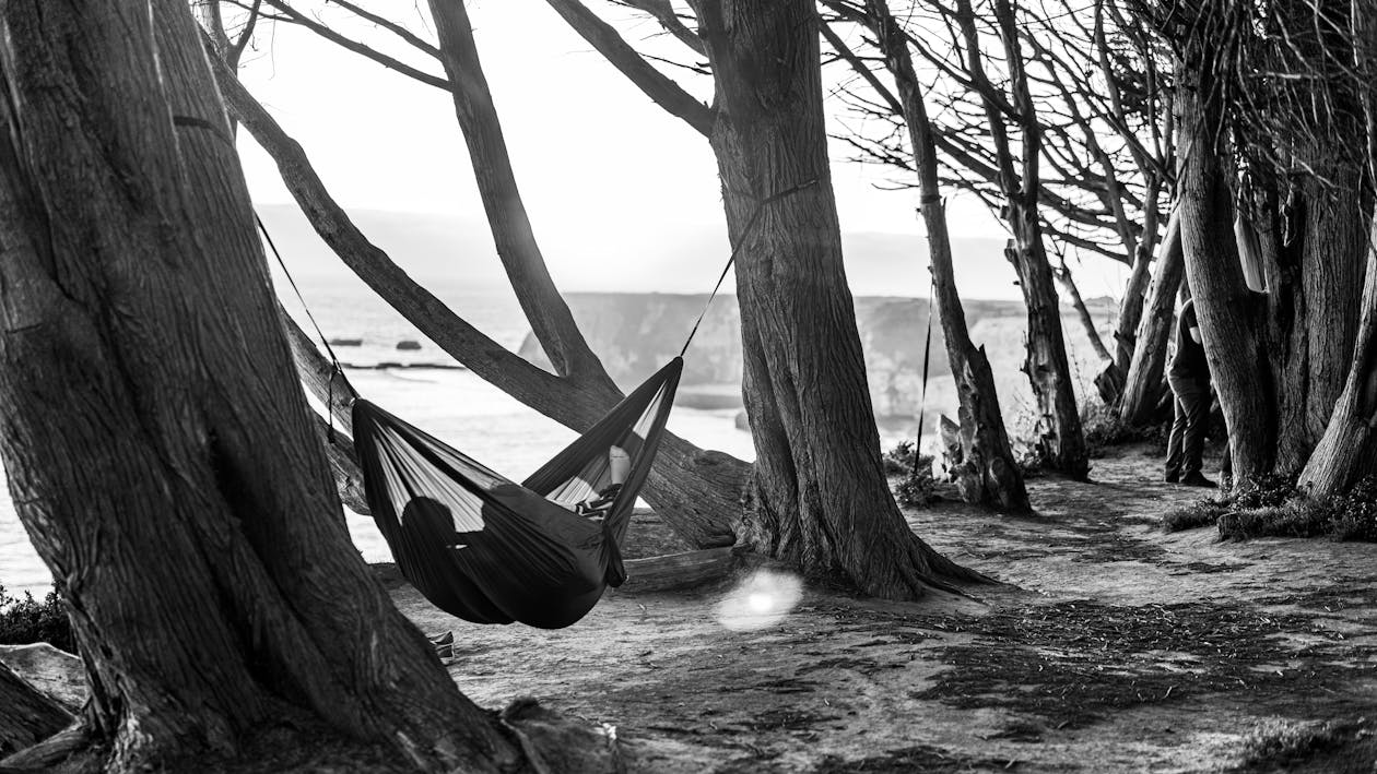 Человек, лежащий в гамаке на фотографии в оттенках серого