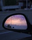 汽车侧镜中映出宁静的日落，烘托出旅途的沉思氛围