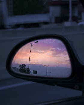 汽车侧镜中映出宁静的日落，烘托出旅途的沉思氛围