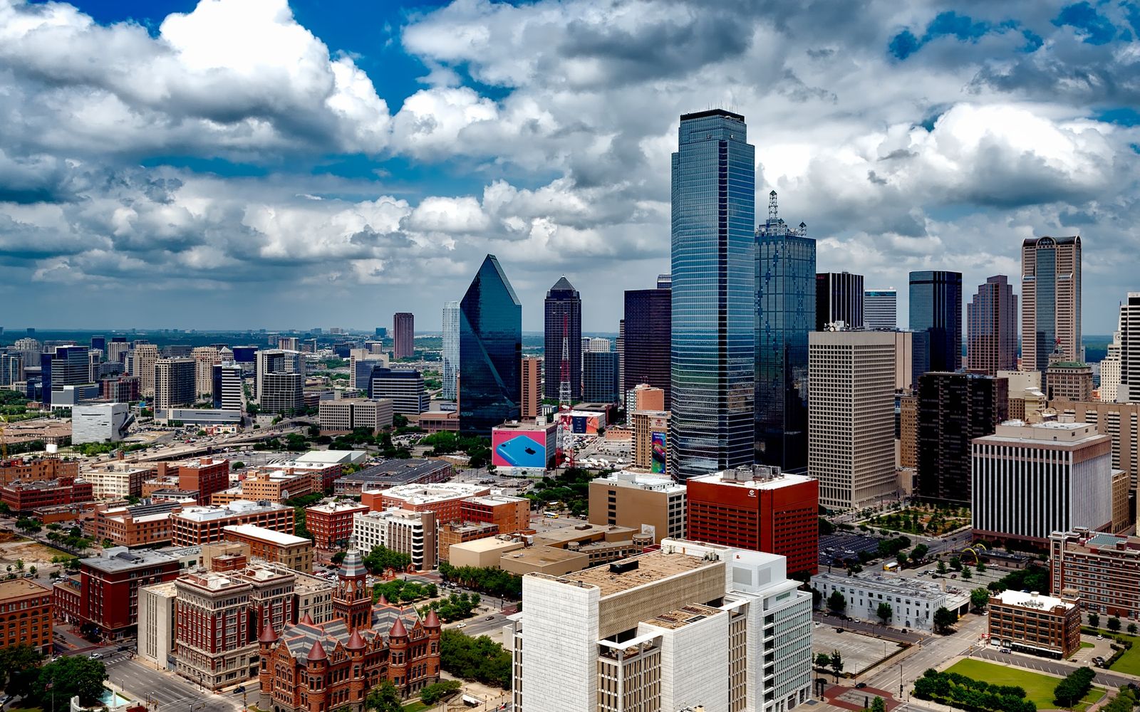 Wide view of the downtown Dallas skyline under a soft, cloud-filled sky.