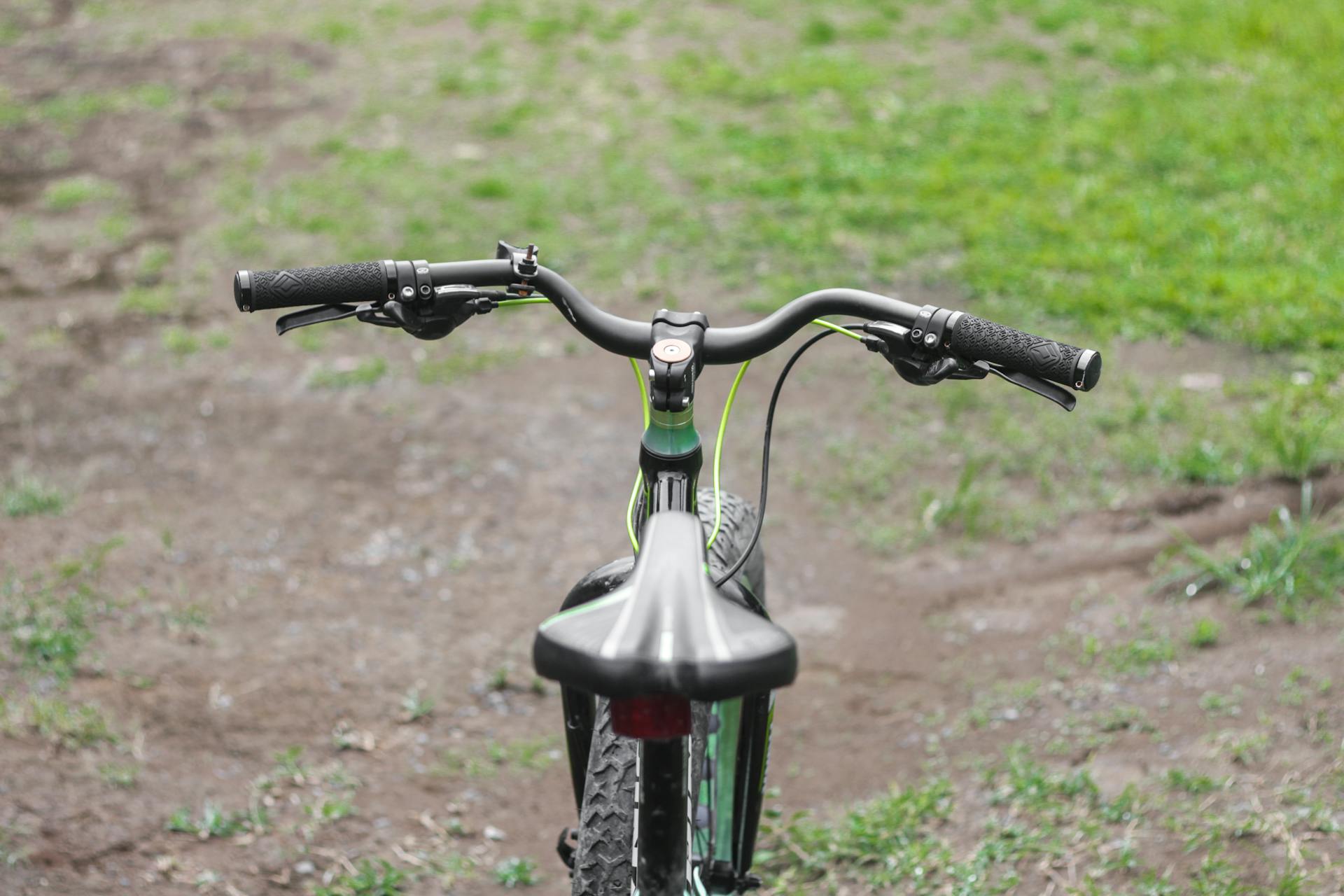 A parked mountain bike on a dirt and grassy path, ideal for outdoor adventure imagery.