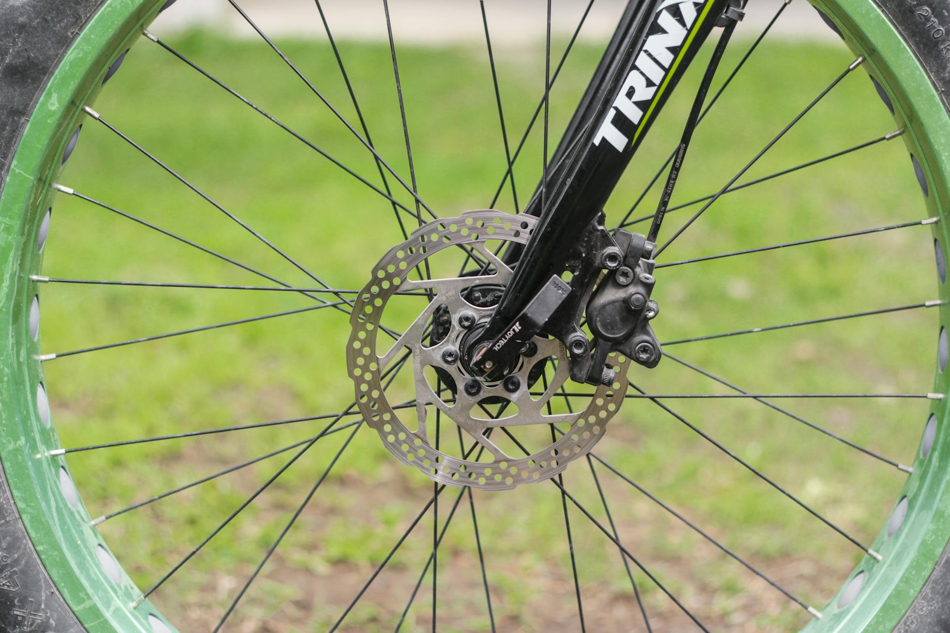 Detailed close-up of a mountain bike wheel featuring a disc brake mechanism on grassy background.