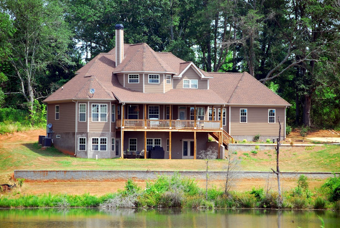 бесплатная Коричневый деревянный дом возле леса и воды Стоковое фото