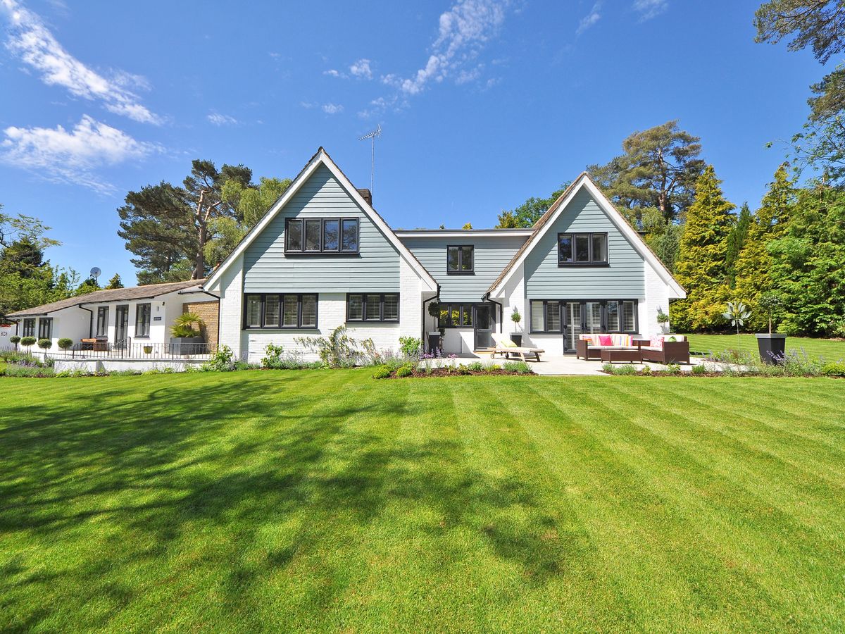 Family home with a large lawn under a clear sky.