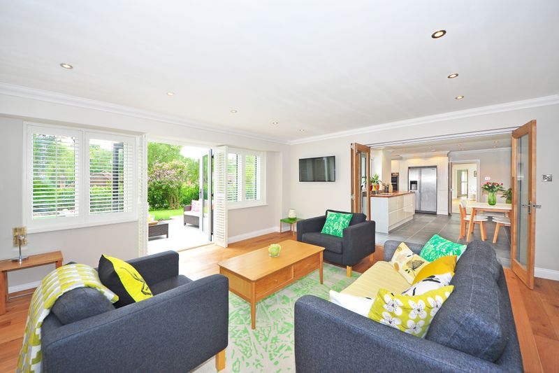 Modern living room with open plan kitchen and garden view, bright and airy ambiance.