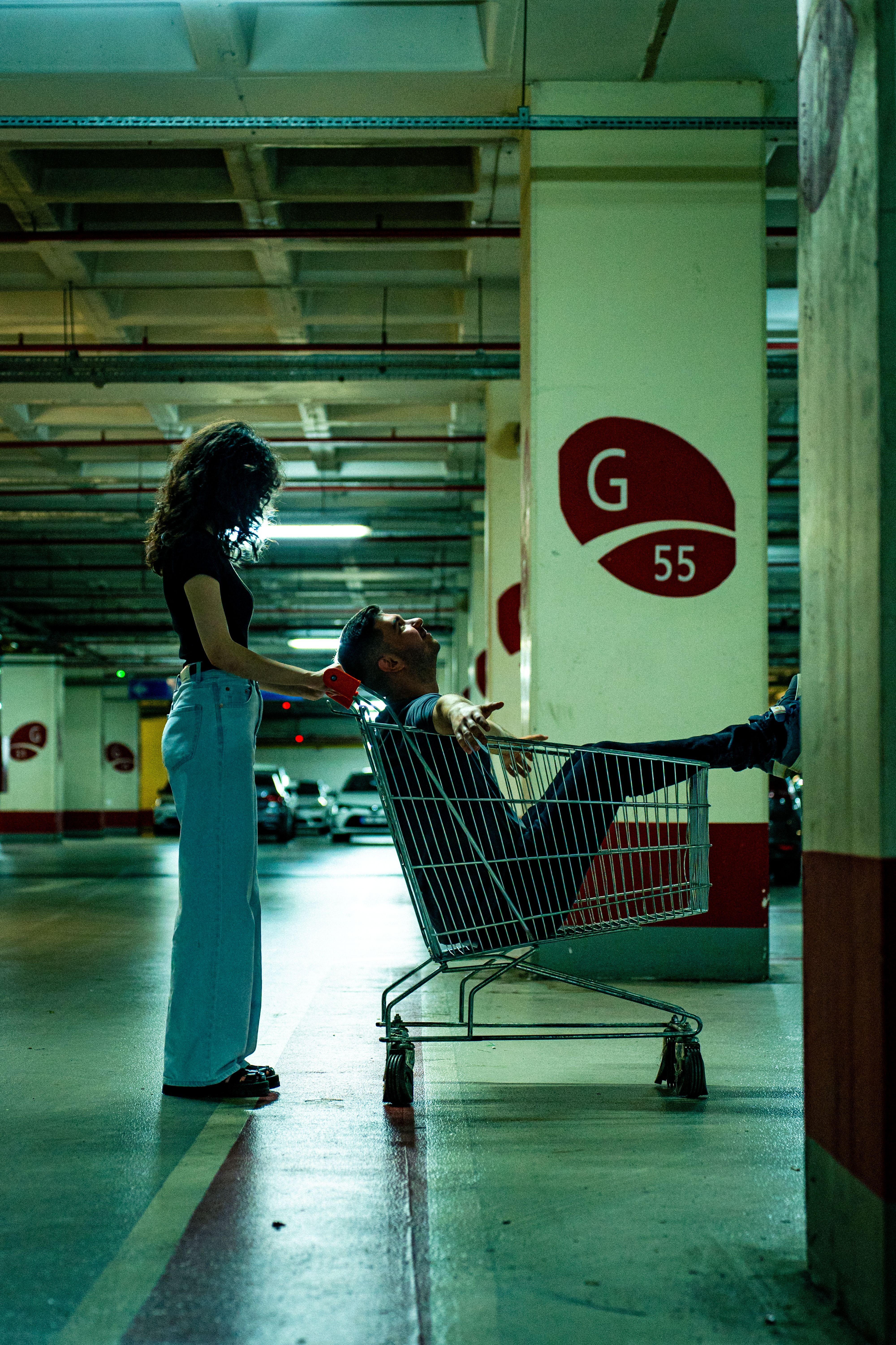 Young couple having fun with shopping cart in dimly lit garage.