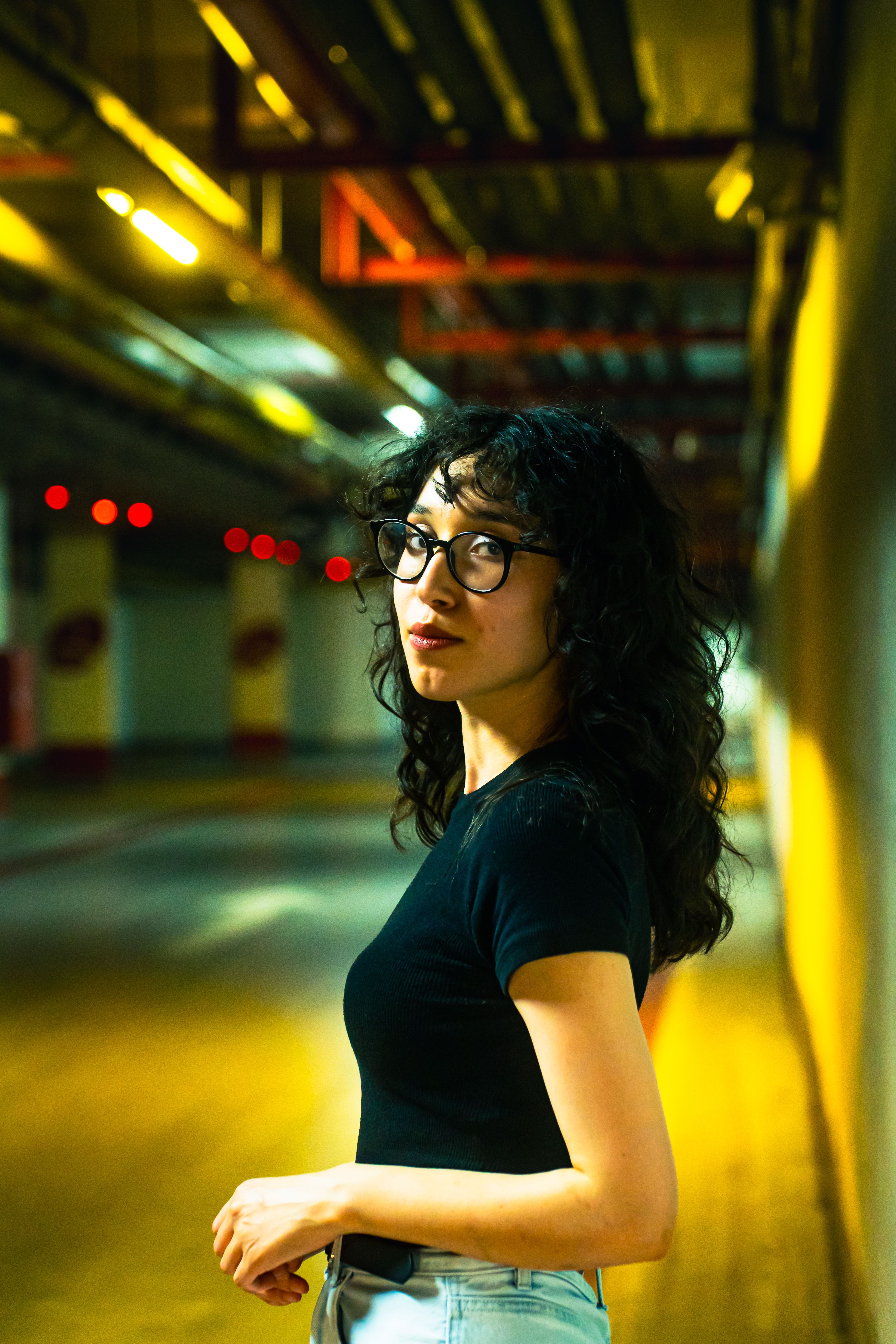 A woman with glasses standing in an underground parking garage · Free ...