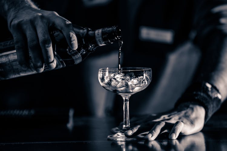 Person Pouring Liquid In Wine Glass