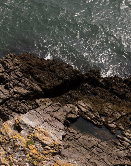 High-angle view of waves crashing on rocky coastline, creating a dramatic seascape.