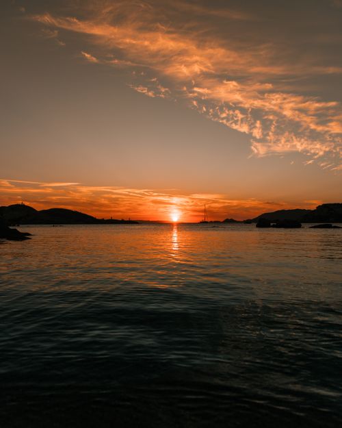 Free Capture the beauty of a serene ocean sunset with vibrant colors reflected on calm waters. Stock Photo