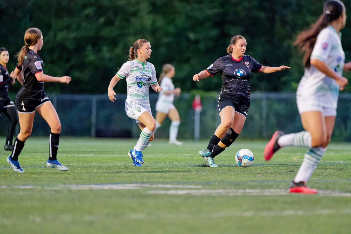 Female soccer players in motion during a competitive match on grass.