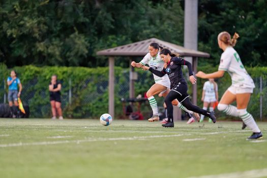Female soccer players in action during a competitive outdoor match, showcasing teamwork and athleticism.