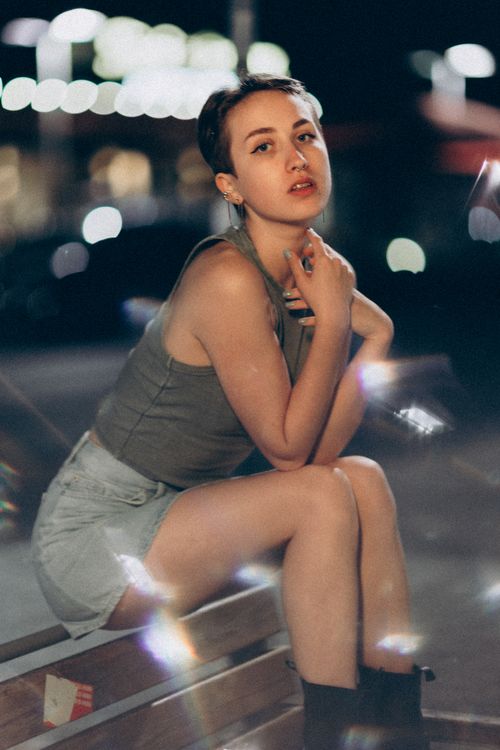 Free Fashionable young woman poses confidently in an urban night setting. Stock Photo