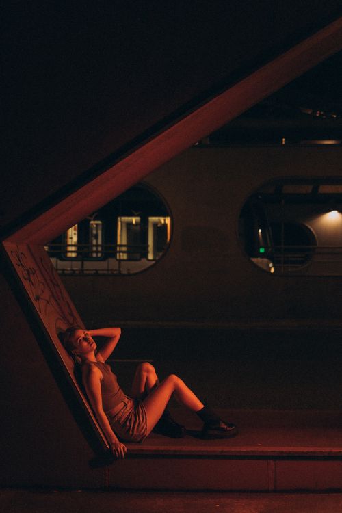 Free A woman in a dramatic pose inside a dark urban architectural setting at night. Stock Photo