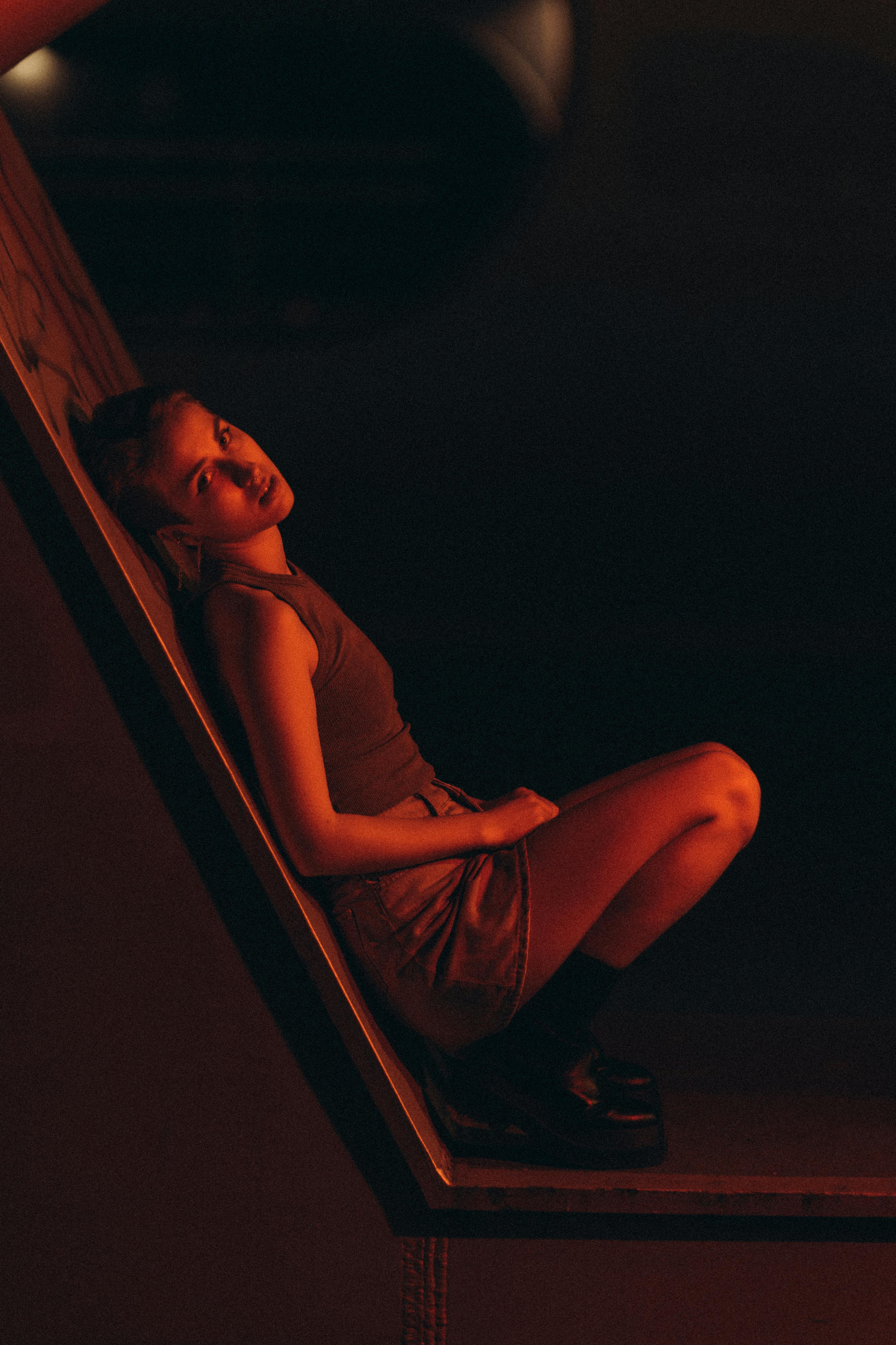 Artistic portrait of a woman posing in dim red light, creating a dramatic and moody atmosphere.