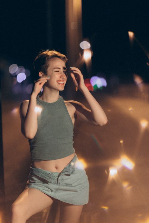 Free A young woman enjoys a night dance with vibrant city lights in the background. Stock Photo