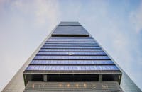 现代摩天大楼的低角度视图令人惊叹，玻璃窗映照着晴朗的天空，突显了建筑创新