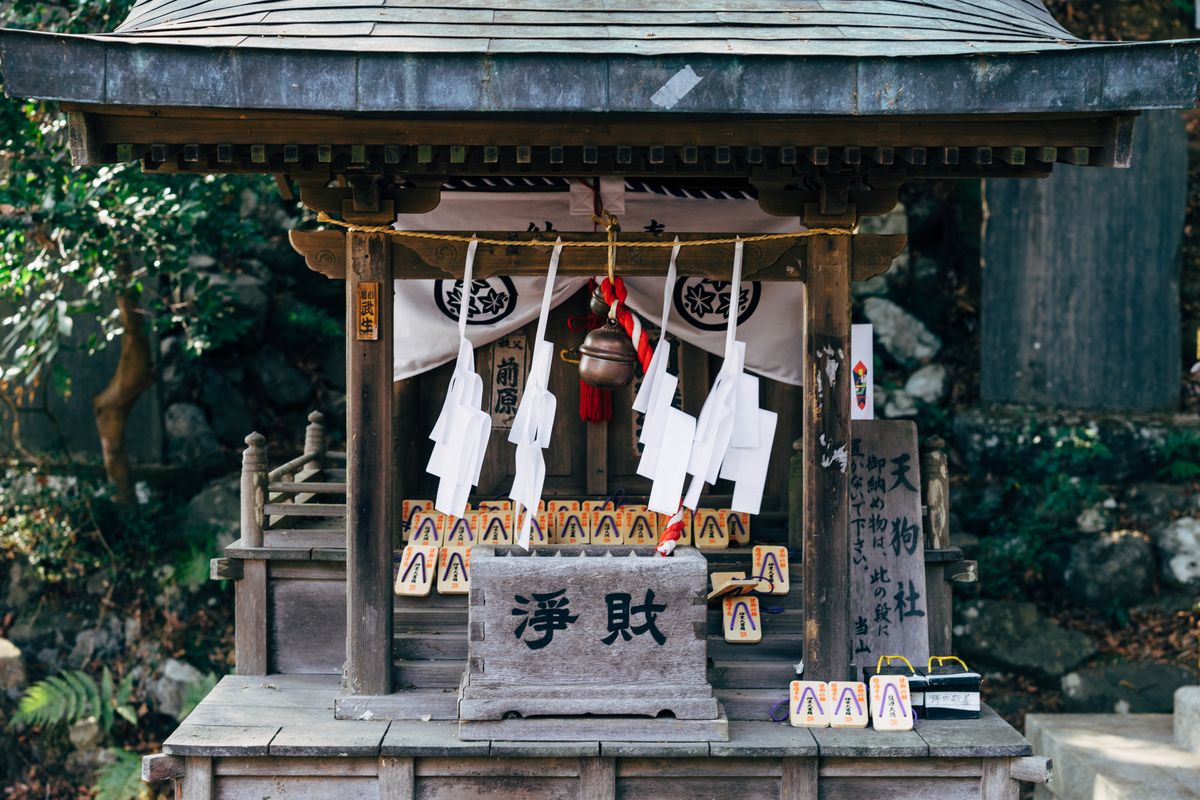 Traditional Japanese Shinto shrine gate (torii) and main hall decorated with lanterns and offerings