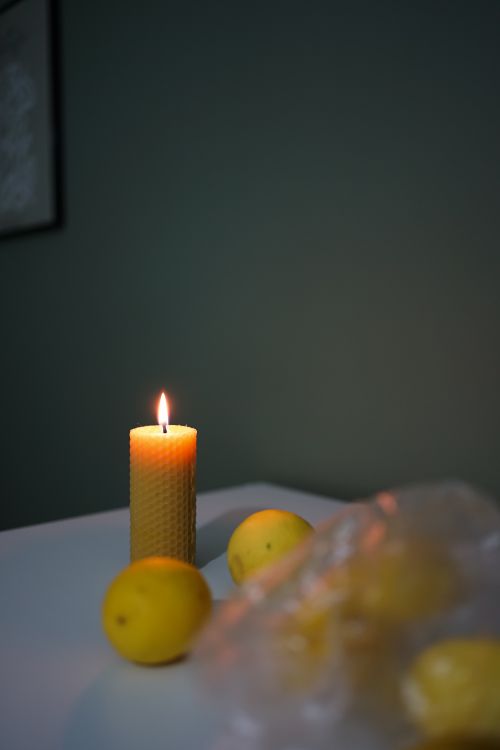 Free A warm candlelit still life scene featuring lemons on a table. Stock Photo