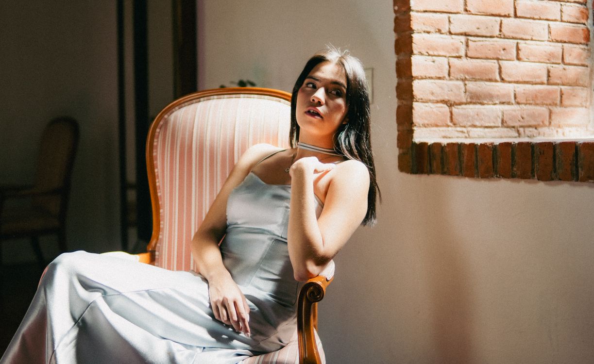 A woman in a white dress sitting in a chair · Free Stock Photo
