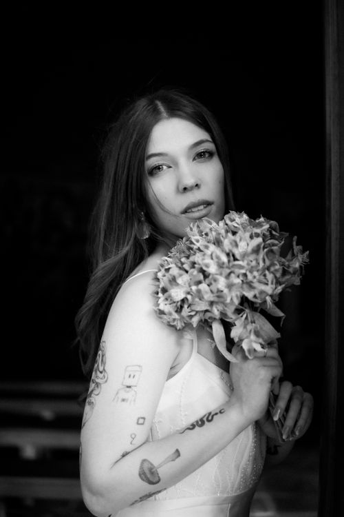 Free Charming black and white portrait of a bride holding flowers, expressing elegance. Stock Photo