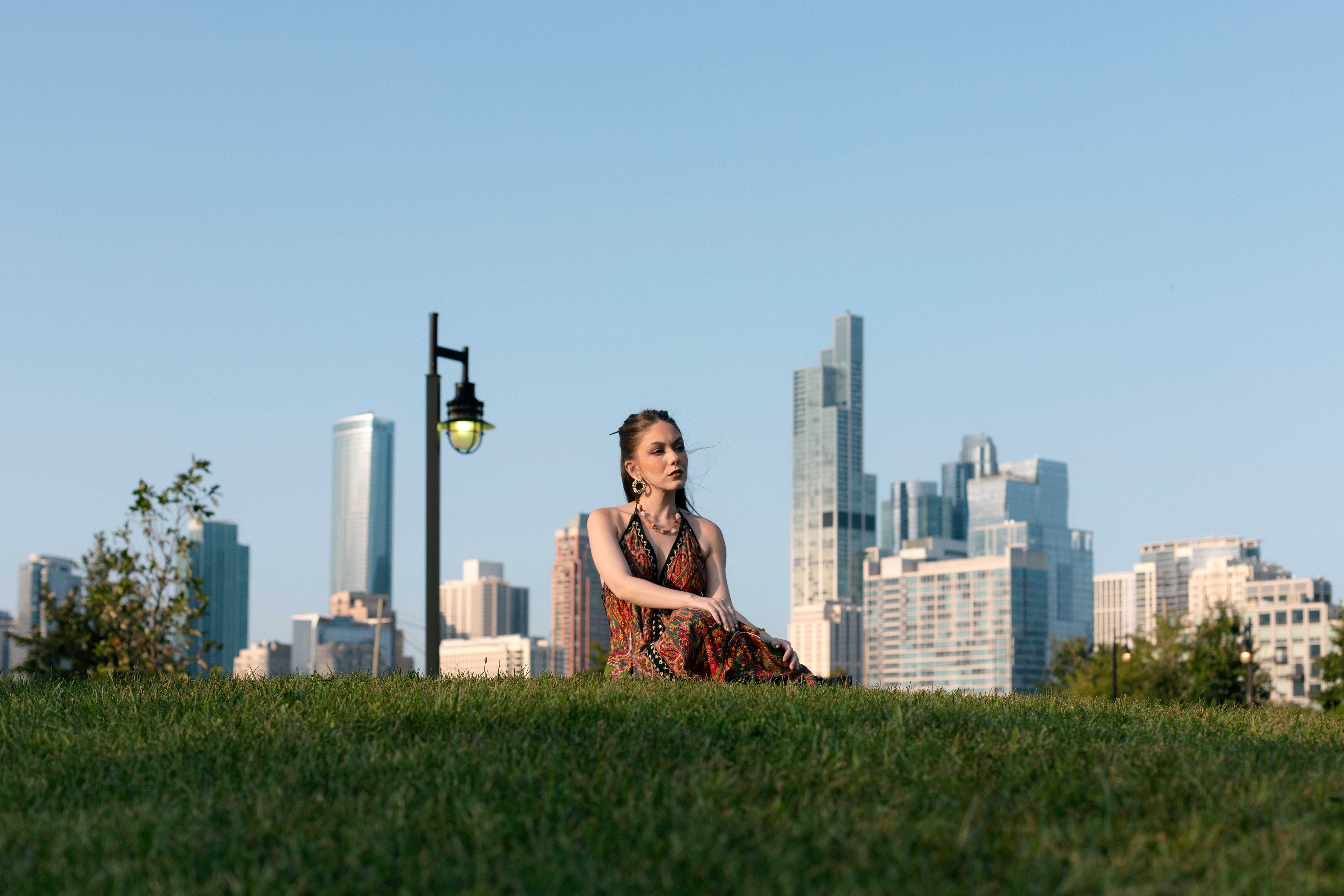A young woman relaxes on a grassy hill with Chicago's skyline in the background.