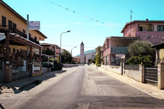 Sunny street scene in Porto San Giorgio, showcasing local architecture and a distant clock tower.
