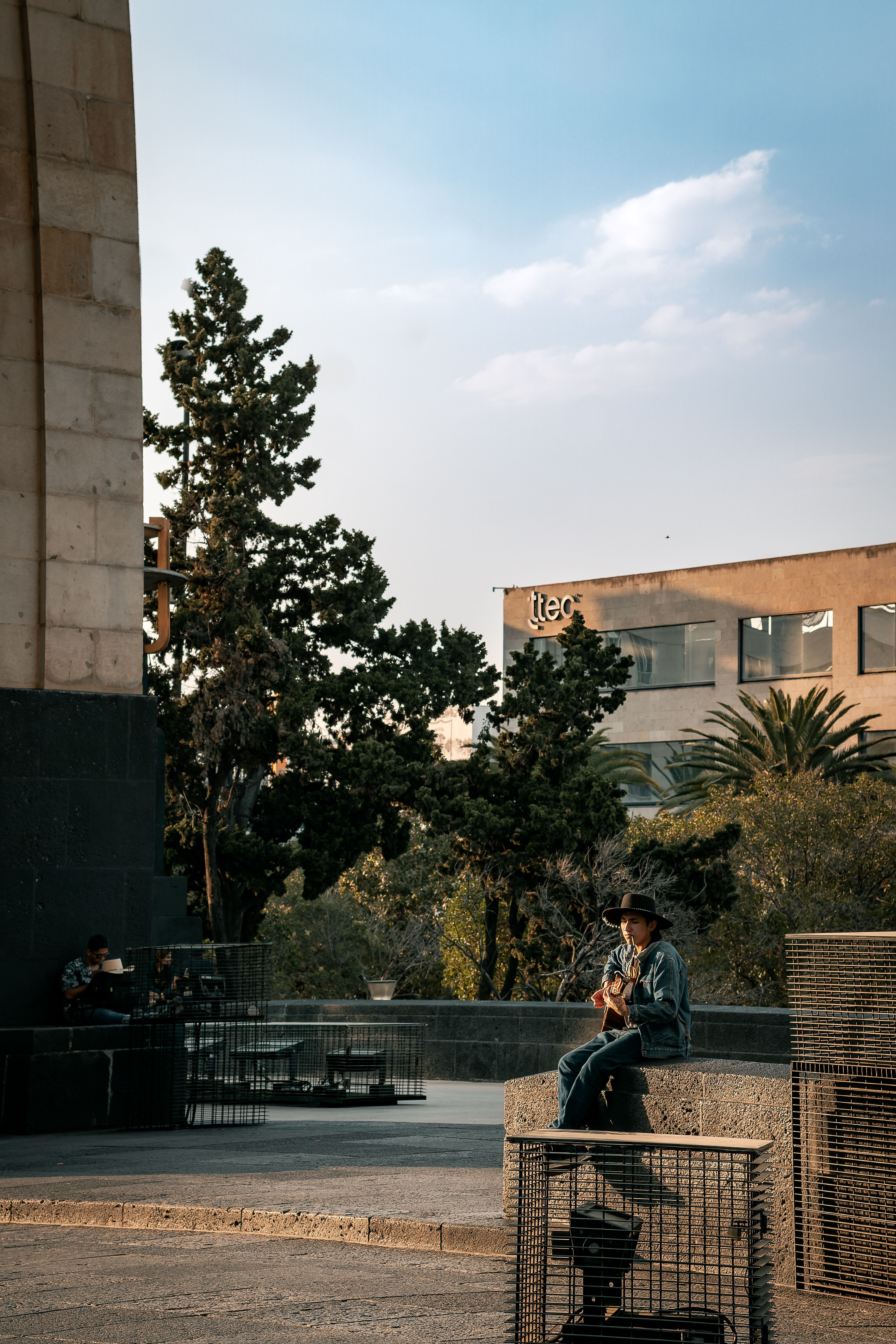 A man sitting on a bench in front of a building · Free Stock Photo