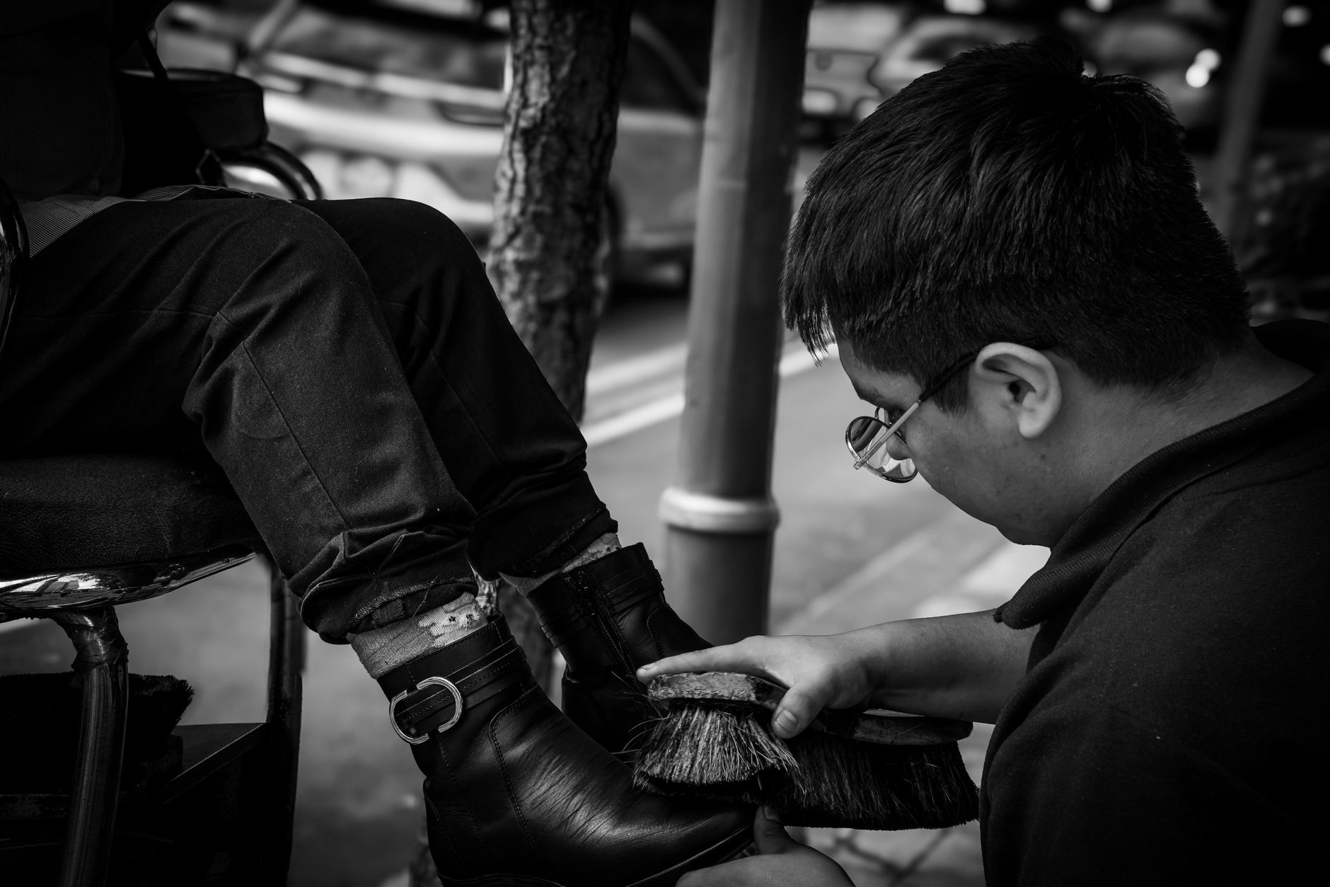 Man polishing shoes on a busy street in Ciudad de México, capturing urban life.