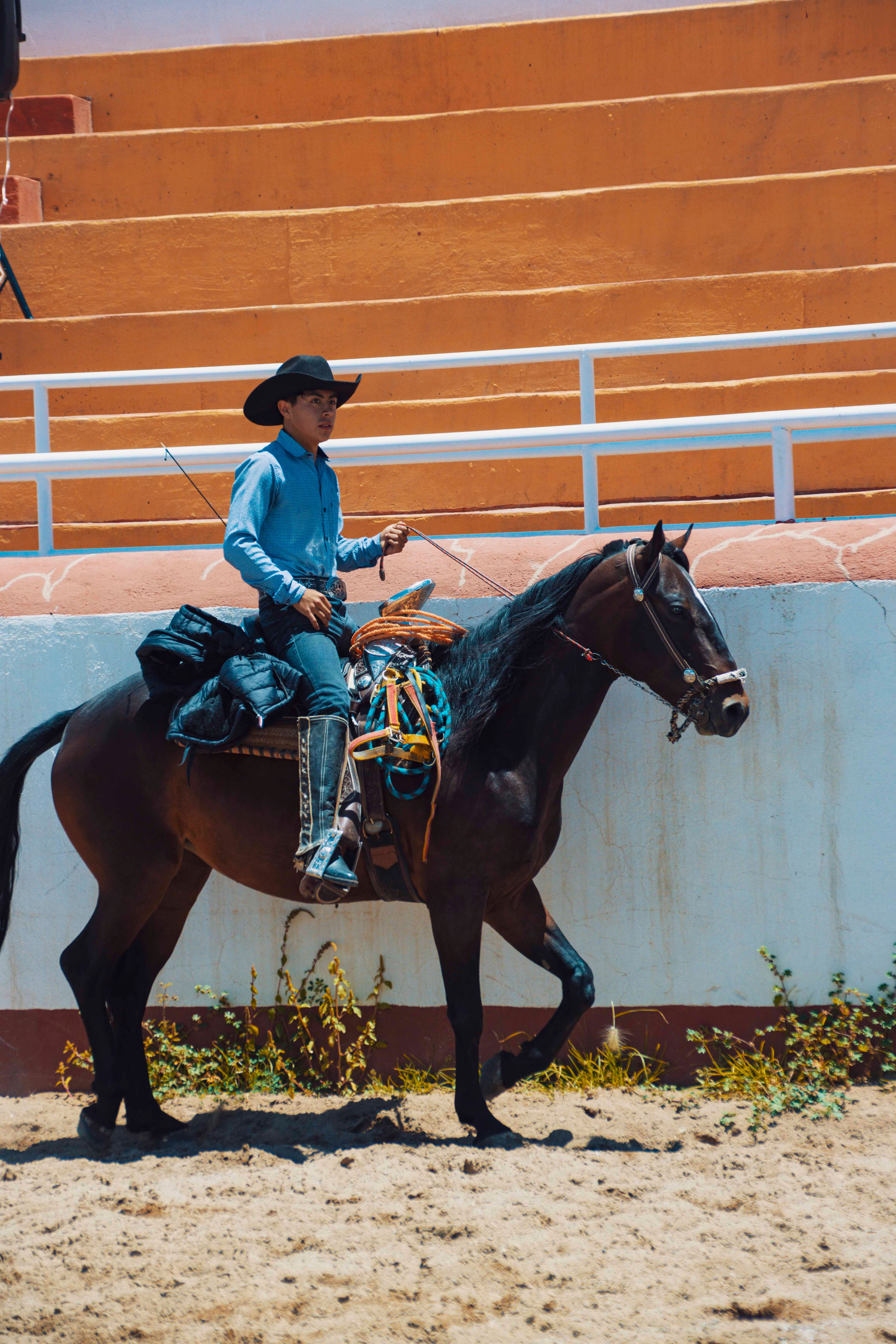 Charro in traditional attire riding a horse at a rodeo event in Mexico.