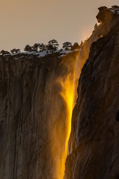 Free Stunning golden waterfall cascading down a rocky cliff during sunset, showcasing nature's beauty in a serene canyon. Stock Photo