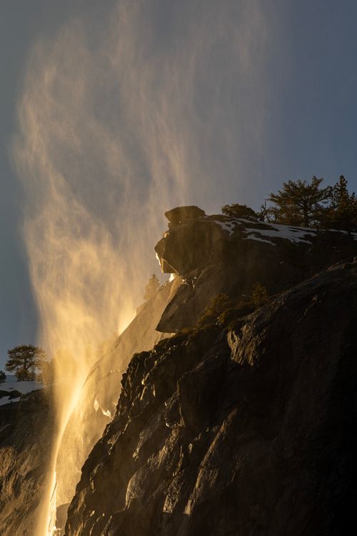 Free Stunning waterfall illuminated by sunset, cascading down rugged mountain landscape. Stock Photo