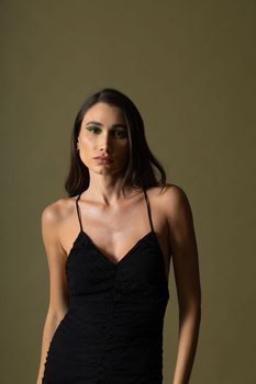 Striking studio portrait of a woman in a black dress on a neutral background, showcasing elegance and style.