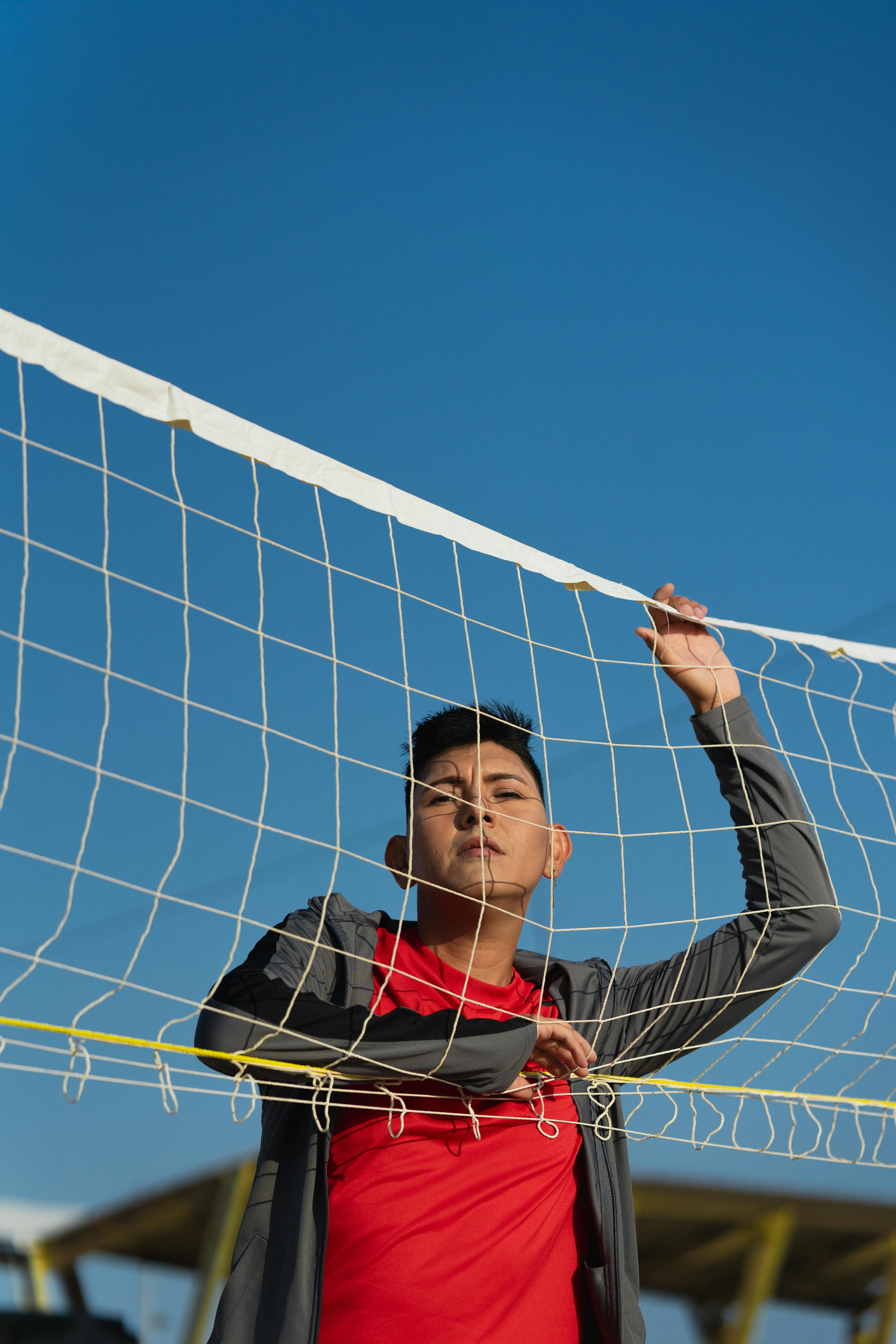 a young man is standing in front of a volleyball net