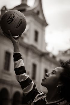 Portrait of a young woman reaching up with a basketball outdoors in Cuenca, Ecuador.