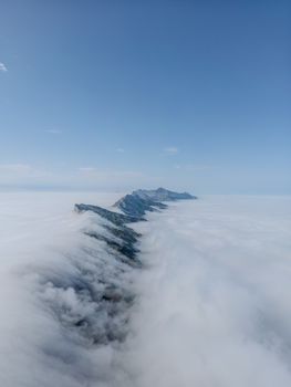 A breathtaking aerial view of snow-capped mountains emerging from a sea of clouds, capturing the serene winter landscape.