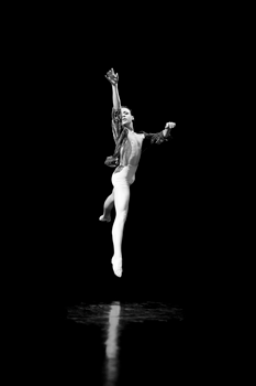 Black and white photograph of a male ballet dancer gracefully leaping in mid-air.