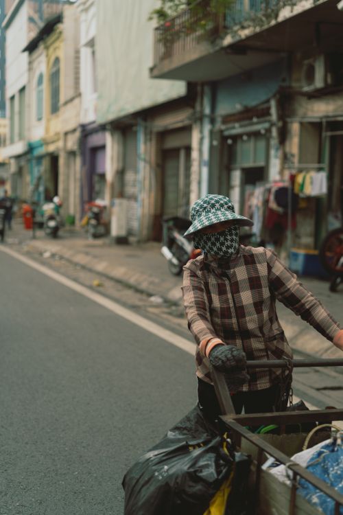 Free A person pushes a cart along a vibrant street in Ho Chi Minh City, showcasing daily life. Stock Photo