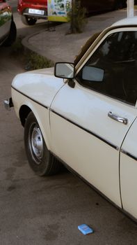 Vintage white car parked on a city street, showcasing retro design and style.