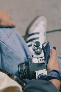 A person holding a vintage camera during a casual outdoor adventure.
