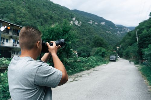 Free A man with a camera captures a scenic view in a mountainous area during daytime. Stock Photo