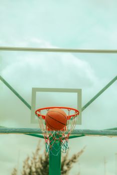 A basketball passing directly through a hoop on an outdoor court, perfect for sports enthusiasts.