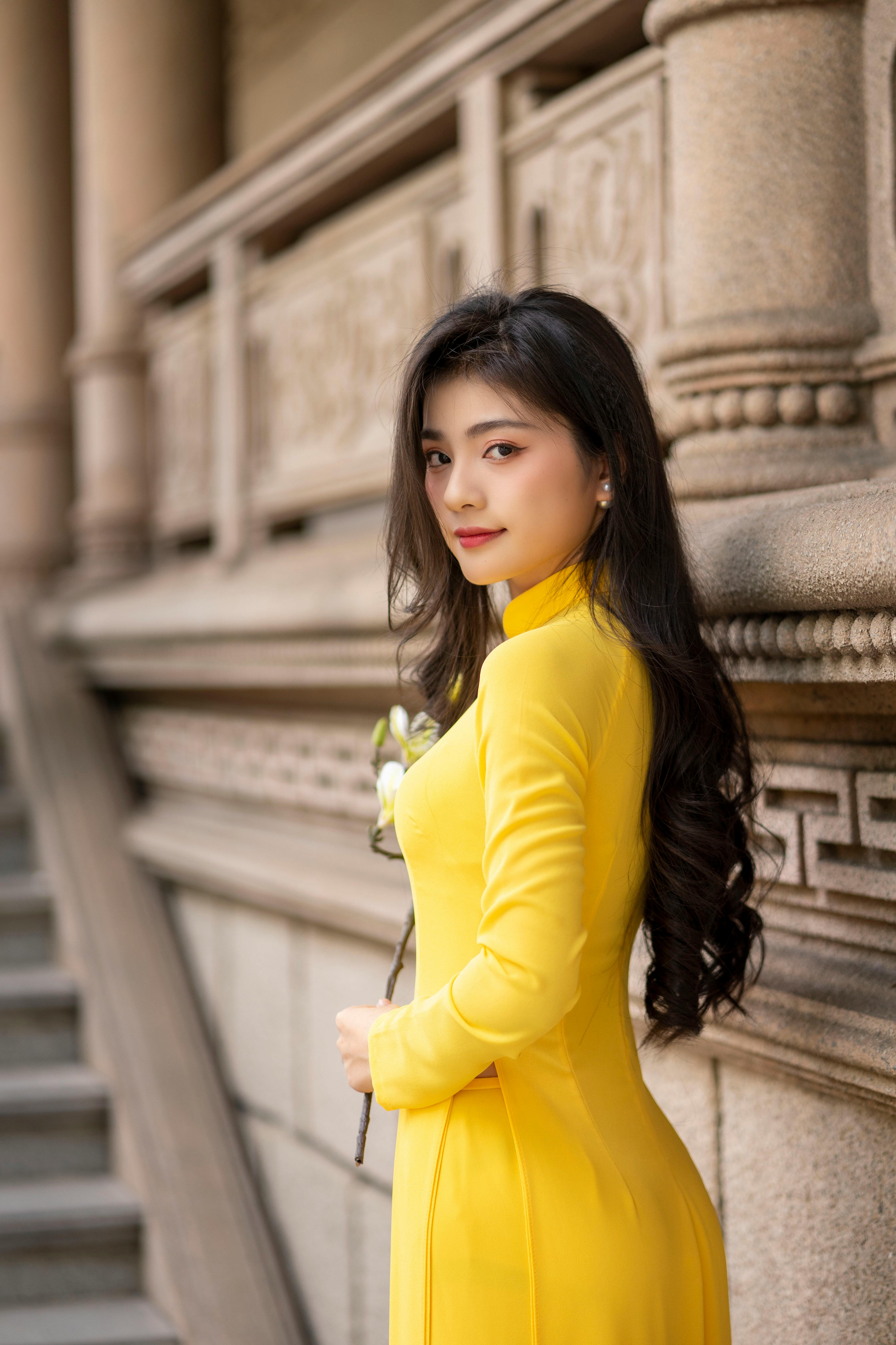 Portrait of a woman in a yellow Ao Dai in Ho Chi Minh City, exuding elegance and style.