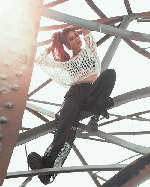 Woman Wearing White Mesh 3/4-sleeved Shirt and Black Pants Sitting on Metal Frame