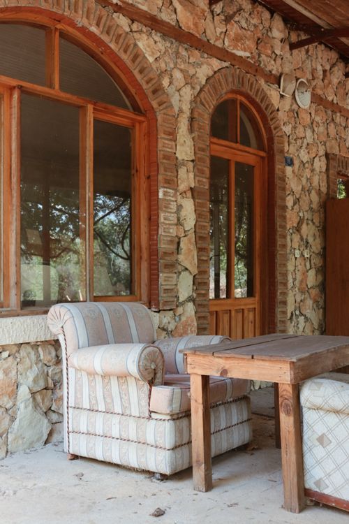 Free Charming rustic setting with stone walls, wooden table, and a comfy armchair, perfect for relaxation. Stock Photo