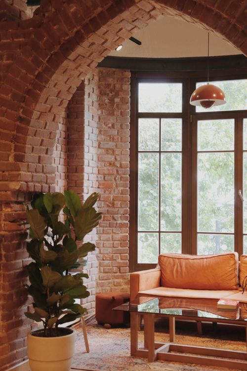Free Warm and inviting living room with brick arches, leather couch, and large windows. Perfect for relaxing. Stock Photo