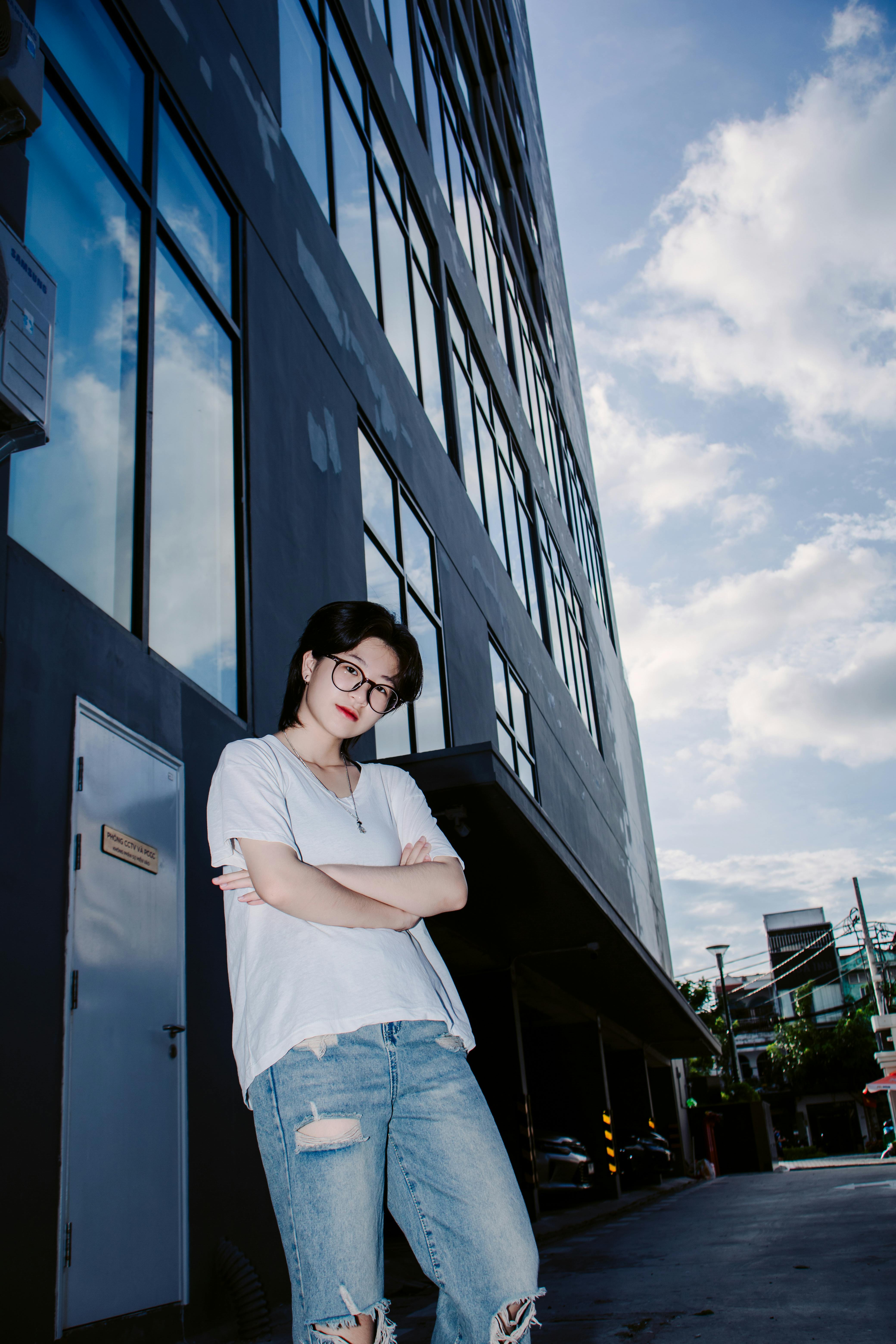 a woman in ripped jeans and white shirt standing on a sidewalk